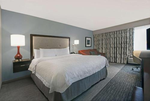 a hotel room with a large bed and a chair at Hampton Inn Greenville/Woodruff Road in Greenville