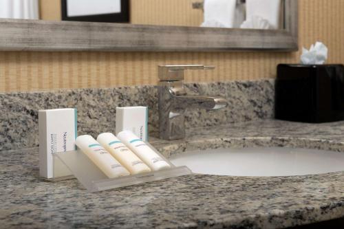 Hilton Garden Inn Gallup في غالوب: مغسلة الحمام فيها صنبورين فرش اسنان