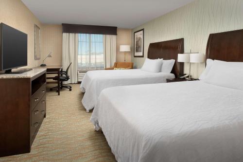 a hotel room with two beds and a flat screen tv at Hilton Garden Inn Gallup in Gallup