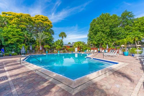 a swimming pool with chairs and trees in the background at Park Shore Resort in Naples