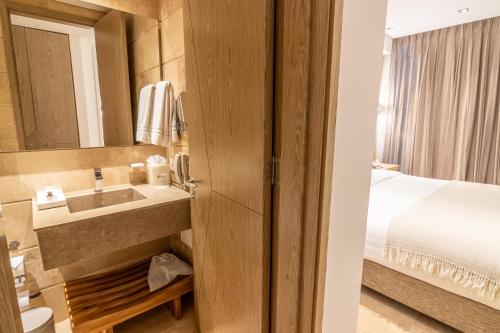 a bathroom with a sink and a bed in a room at GHL Arsenal Hotel in Cartagena de Indias