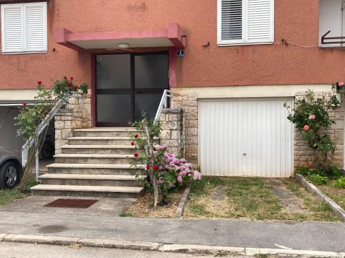 una casa con una puerta de garaje blanca y algunas flores en Home sweet home, en Poreč