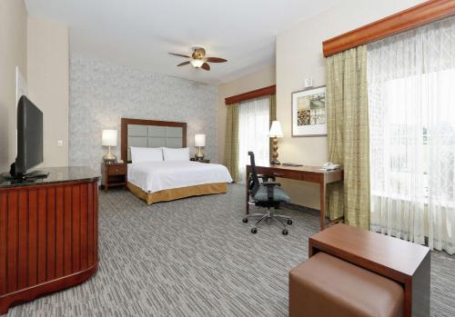 a hotel room with a bed and a desk and a television at Homewood Suites Hagerstown in Hagerstown