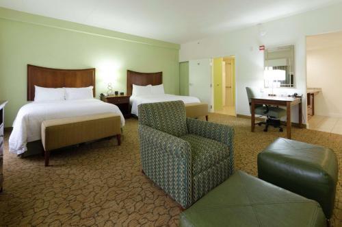um quarto de hotel com duas camas e uma cadeira em Hampton Inn Hickory em Hickory