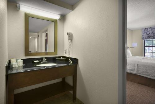 a bathroom with a sink and a mirror and a bed at Hampton Inn Helen in Helen