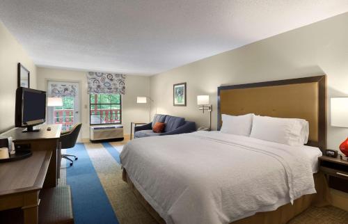ein Hotelzimmer mit einem großen Bett und einem Schreibtisch in der Unterkunft Hampton Inn Helen in Helen