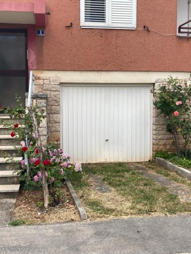 una puerta de garaje blanca con flores delante de una casa en Home sweet home, en Poreč