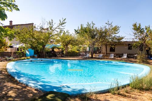 Hotel Rural Fuente La Teja في غويخار سييرا: مسبح ازرق كبير في ساحه بها اشجار