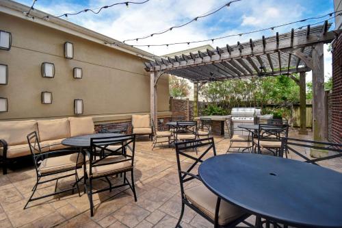 eine Terrasse mit Tischen, Stühlen und einer Pergola in der Unterkunft Homewood Suites By Hilton HOU Intercontinental Airport in Houston