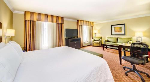 a hotel room with a large bed and a living room at Hampton Inn & Suites Scottsboro in Scottsboro