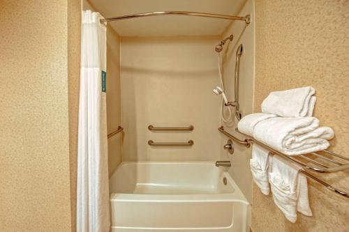 a bathroom with a tub and a shower with towels at Hampton Inn Ashland in Ashland