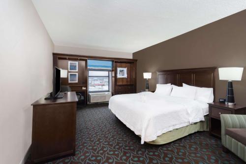 a hotel room with a bed and a flat screen tv at Hampton Inn Terre Haute in Terre Haute