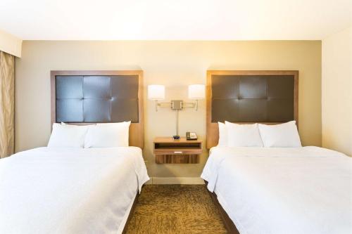 two beds in a hotel room with white sheets at Hampton Inn Havelock in Havelock