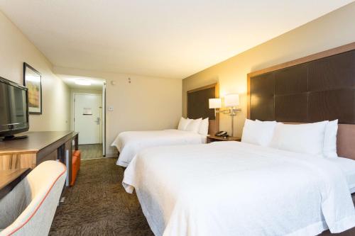 a hotel room with two beds and a flat screen tv at Hampton Inn Havelock in Havelock