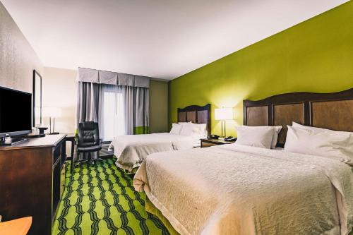 a hotel room with two beds and a flat screen tv at Hampton Inn Niagara Falls/ Blvd in Niagara Falls