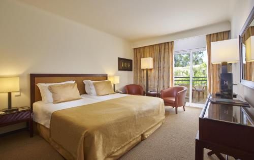 um quarto de hotel com uma cama e uma varanda em PortoBay Falesia em Albufeira