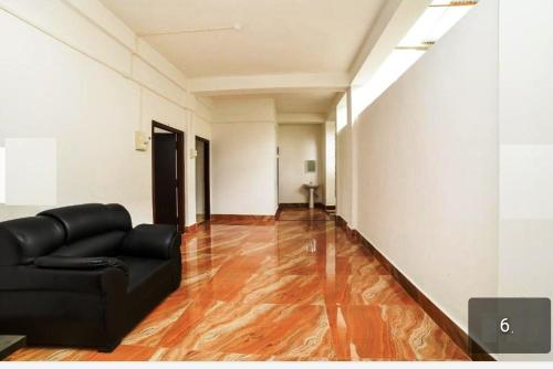 a living room with a black couch and a wooden floor at JRB RESIDENCY in Dibrugarh