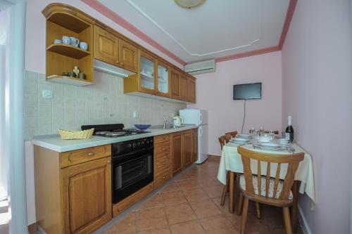 a kitchen with wooden cabinets and a table with a dining room at Apartment Nina in Promajna