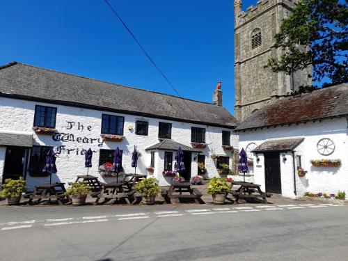 a white building with tables and chairs in front of it at The Weary Friar Inn in Pillaton