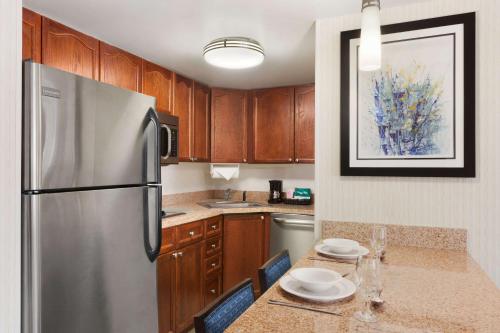 a kitchen with a stainless steel refrigerator and wooden cabinets at Homewood Suites by Hilton Wilmington-Brandywine Valley in Talleyville