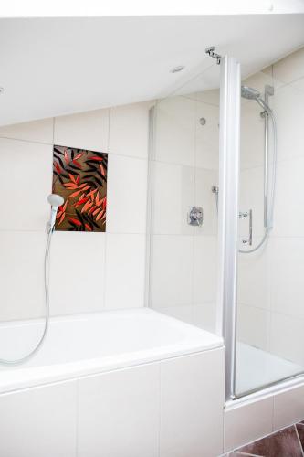 a white bathroom with a shower and a tub at Ferienwohnung - Haus am Sonnenhang in Wertach
