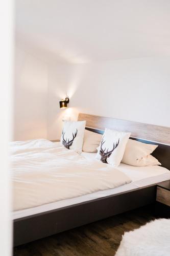 a large bed with white sheets and pillows at Ferienwohnung - Haus am Sonnenhang in Wertach