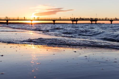 una playa con un muelle en el océano al atardecer en Lomma Camping, en Lomma