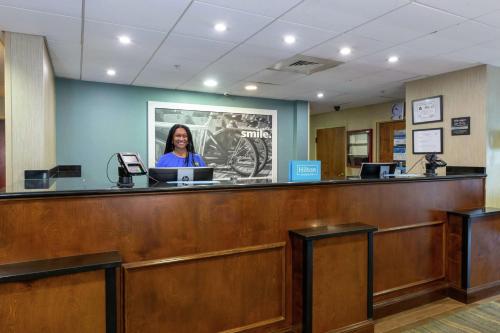 a woman sitting at a counter in a waiting room at Hampton Inn Winston-Salem Hanes Mall in Winston-Salem