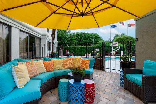 a patio with a blue couch and a yellow umbrella at Hampton Inn Winston-Salem Hanes Mall in Winston-Salem