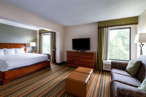 a hotel room with a bed and a tv and a couch at Hampton Inn Winston-Salem Hanes Mall in Winston-Salem