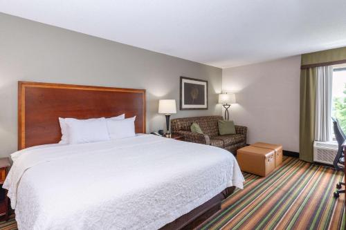 a hotel room with a bed and a chair at Hampton Inn Winston-Salem Hanes Mall in Winston-Salem