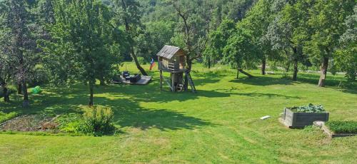 ein Park mit einem Baumhaus im Gras in der Unterkunft Šilarjeva huba Apartment in Bohinjska Bistrica