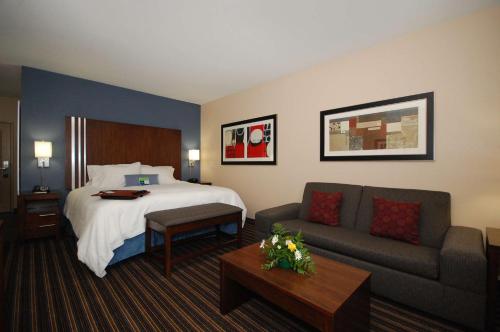 Habitación de hotel con cama y sofá en Hampton Inn Jackson/Flowood - Airport Area MS, en Luckney