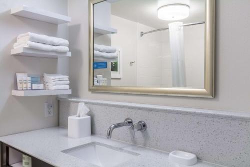 a bathroom with a sink and a mirror and towels at Hampton Inn Jackson Pearl Intrntl Airport in Pearl