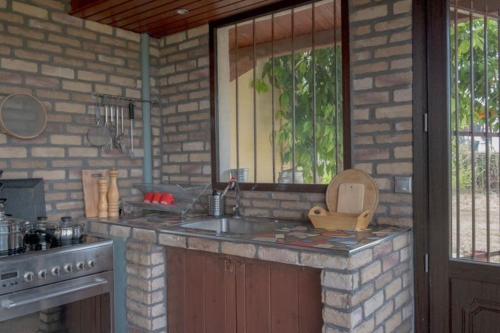 - une cuisine avec un évier et un mur en briques dans l'établissement Leveniotis Villa, à Angelochórion