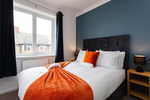 a bedroom with a bed with an orange blanket on it at Plessey House Blyth by #ShortStaysAway in Cowpen