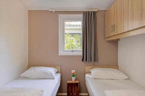 two beds in a room with a window at lodge De Winterkoning in Nunspeet