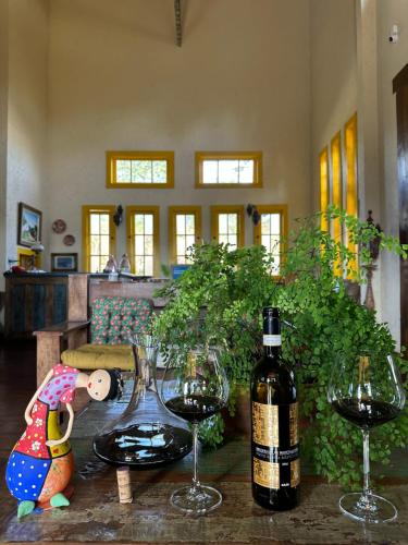 a table with two glasses and a bottle of wine at A Casa Vermelha Hospedaria in Tiradentes