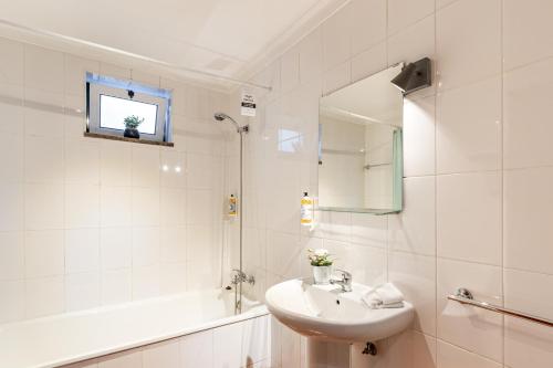 a white bathroom with a sink and a tub and a mirror at Casa da Sé Historic next to Braga Cathedral by Sé Apartamentos in Braga