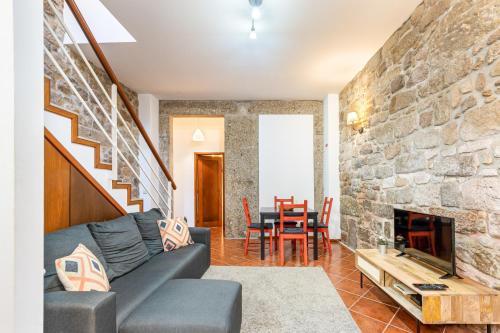a living room with a couch and a stone wall at Casa da Sé Historic next to Braga Cathedral by Sé Apartamentos in Braga