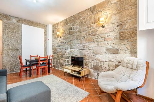 a living room with a stone wall at Casa da Sé Historic next to Braga Cathedral by Sé Apartamentos in Braga