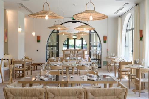 ein Restaurant mit Tischen, Stühlen und Fenstern in der Unterkunft Le Couvent des Minimes Hôtel & Spa L'Occitane in Mane