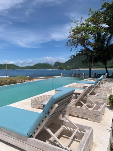 a swimming pool with lounge chairs and the water at Kacchapa Beach Resort and Restaurant in Sekongkang