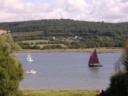 two boats on a lake with a red sail at Au gré des marées, 2 chambres avec petit déjeuner in Hanvec
