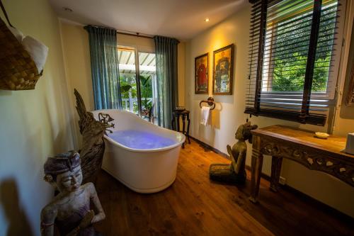 a bathroom with a tub and a statue in it at Villa Vanille in Boisseron