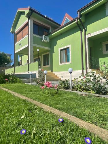 een groen huis met paarse bloemen in de tuin bij Casa Alleria in 2 Mai
