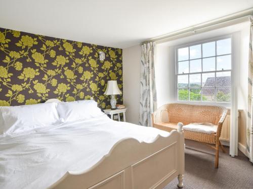 a bedroom with a bed with a yellow floral wallpaper at Thatched Cottage in Bridport