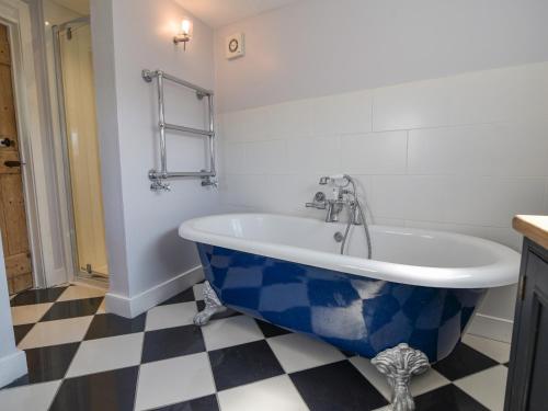 uma banheira azul e branca na casa de banho em Thatched Cottage em Bridport