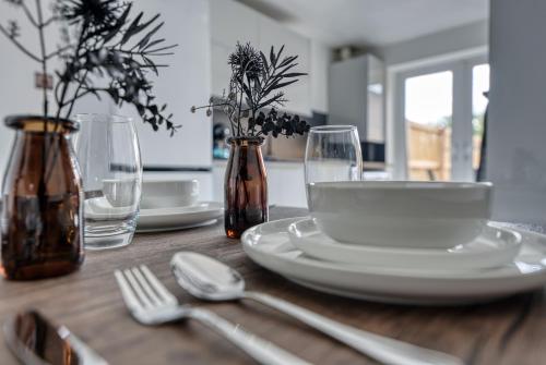 een houten tafel met borden en keukengerei erop bij Aryas Homes Oxford - Headington in Oxford