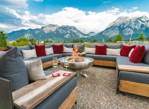 a patio with couches and a fire pit with mountains at Hotel Das Rübezahl in Schwangau